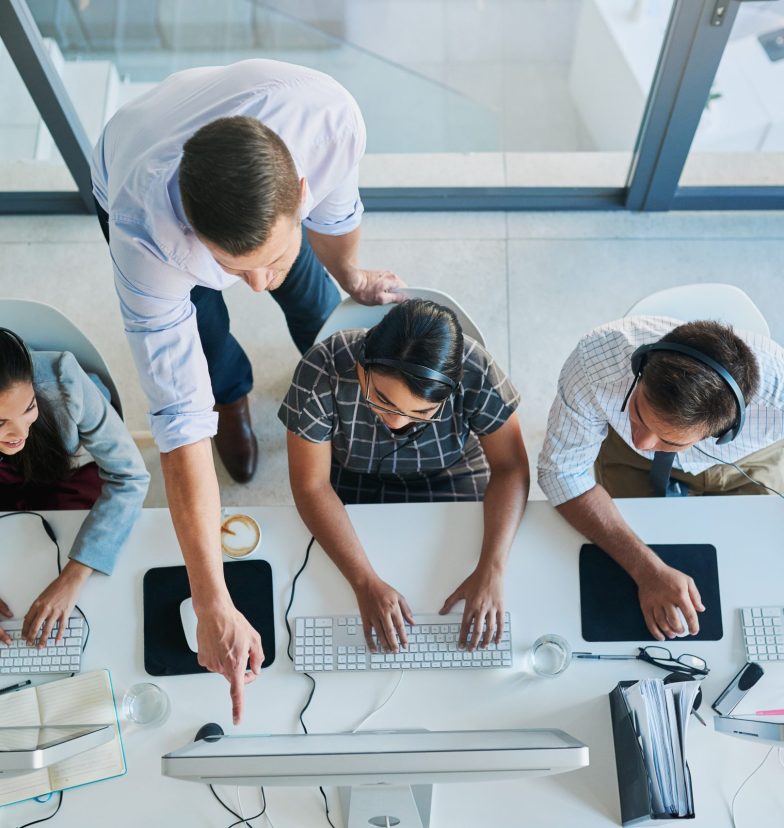 High angle shot of a man assisting his colleagues in a call center