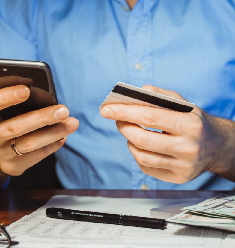 Stressed young businessman calculating monthly Family expenses, taxes, checking bank account balance credit card payment, Income at home night. Cropped shot male hands paying bill online on smartphone